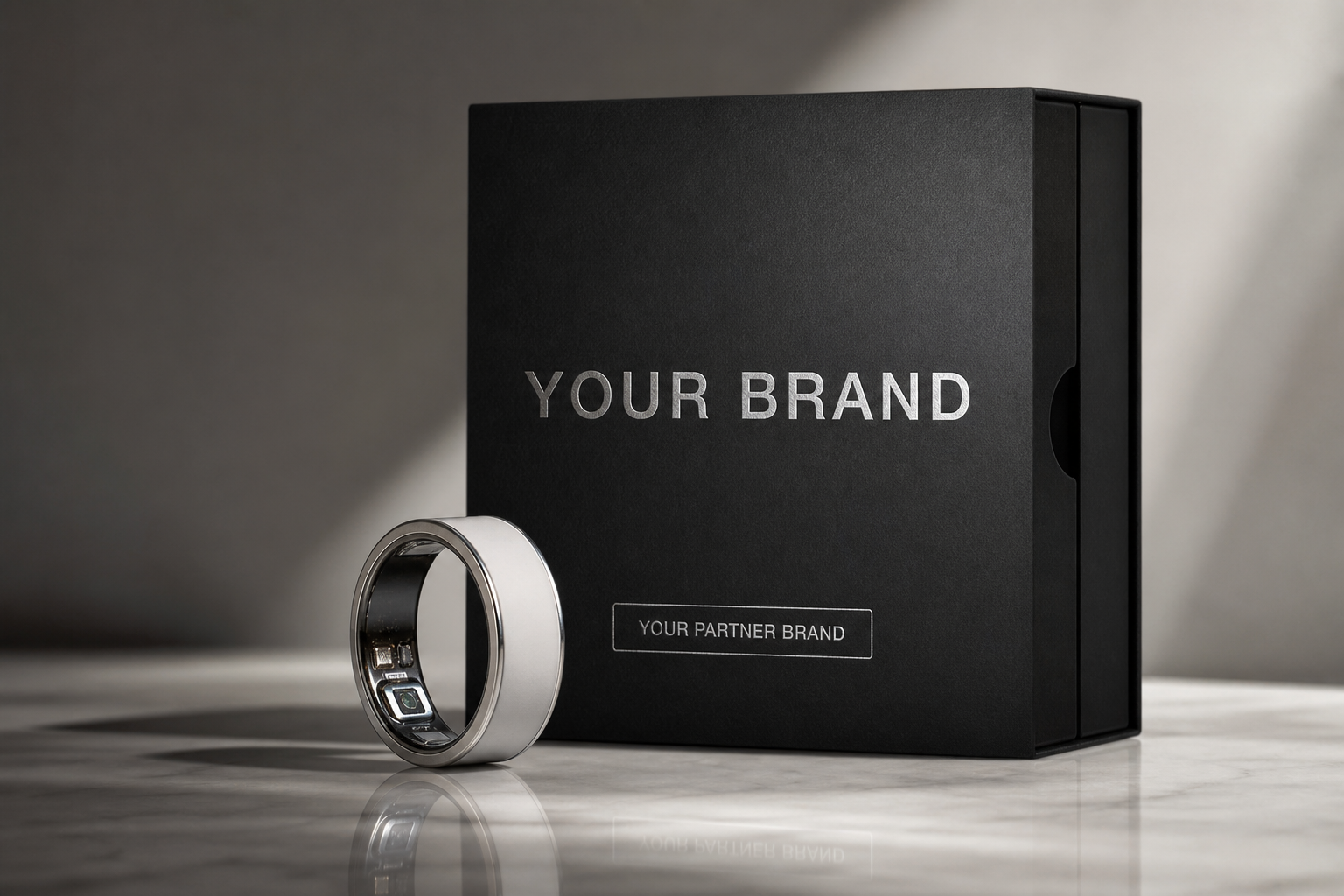 Smart ring beside premium packaging sleeve printed with YOUR BRAND for co-brand retail mockups
